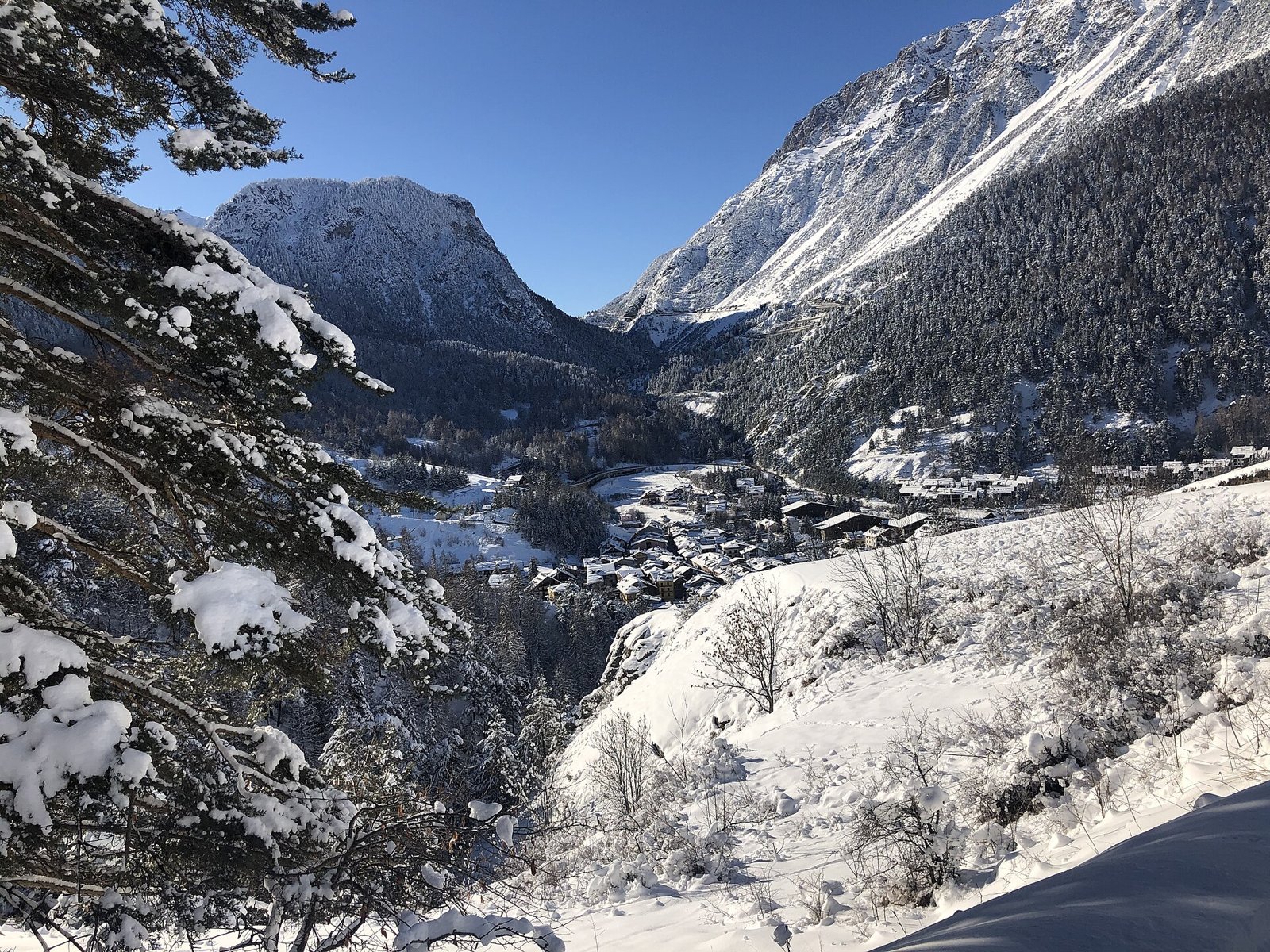 Cesana Torinese innevata vista da Sansicario, tra boschi e montagne dell'alta Val Susa