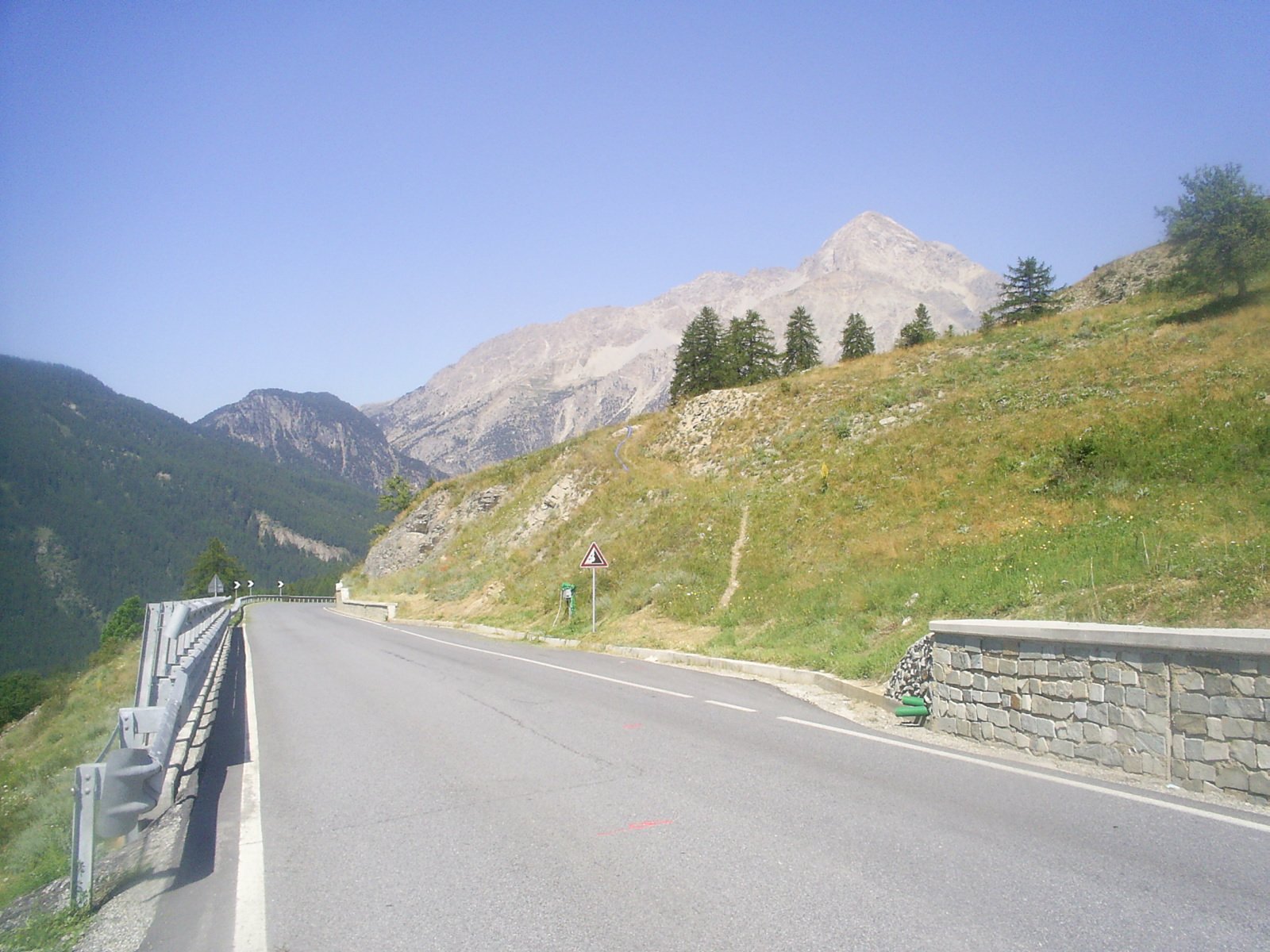 La strada statale 23 che sale al Colle del Sestriere tra prati e larici, con il Monte Chaberton sullo sfondo