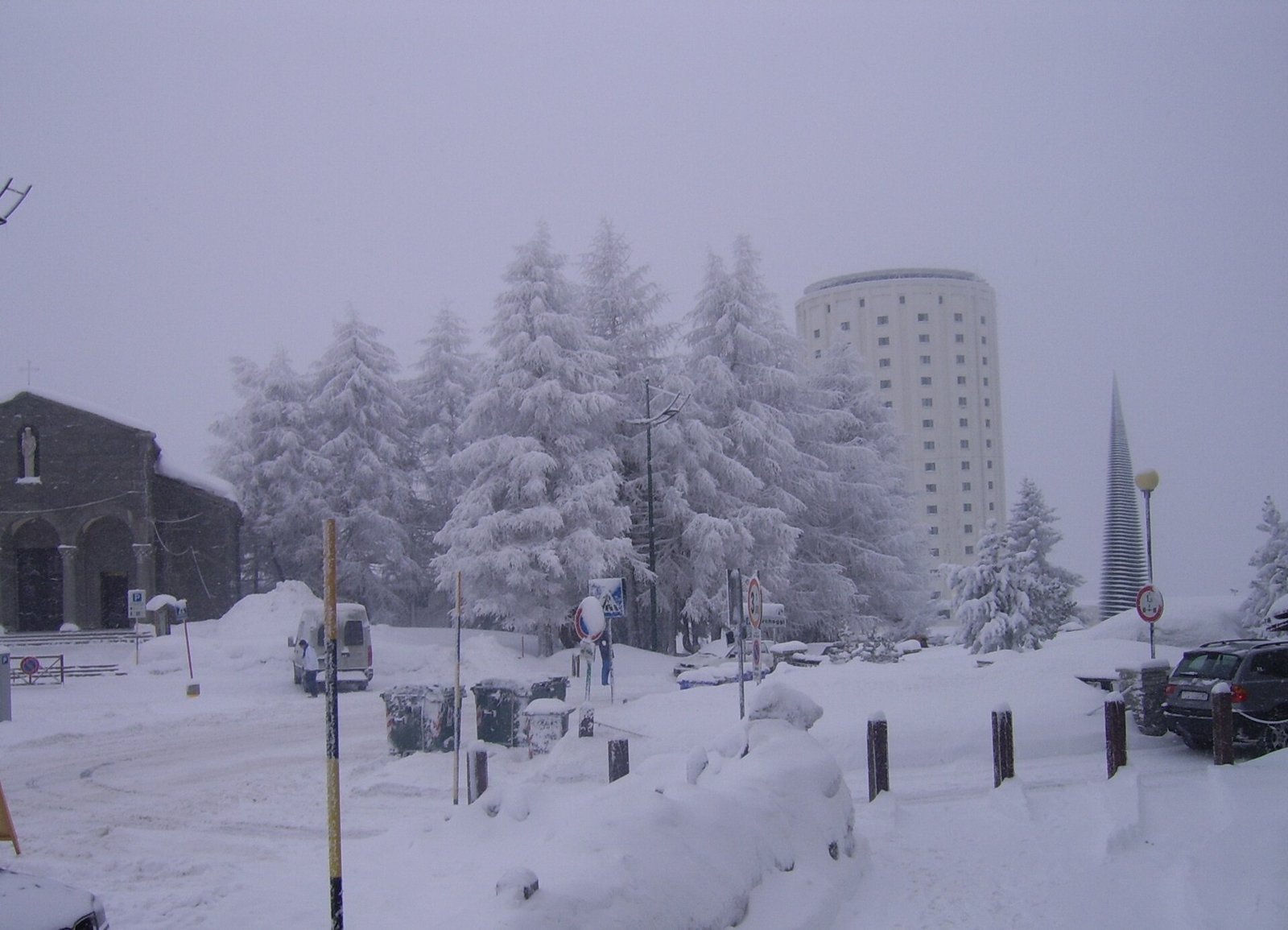 Sestriere sotto una fitta nevicata, con abeti carichi di neve e una delle torri cilindriche sullo sfondo